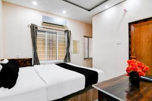 um quarto com uma cama, uma mesa e uma janela em Hotel O Narayana RN Tagore Hospital Formerly Lantern Guest House em Calcutá