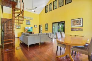 een woonkamer met gele muren en een houten tafel bij Kingfisher Vista in Cable Beach