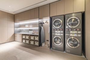 a laundry room with three washing machines and a sink at JI Hotel Shanghai Pudong Airport Zhuqiao in Nanhui