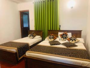 2 camas en una habitación con cortinas verdes en Lady Maccllum's Bungalow Stone Nuwareliya Sri Lanka, en Nuwara Eliya