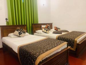 2 camas en una habitación con cortinas verdes en Lady Maccllum's Bungalow Stone Nuwareliya Sri Lanka, en Nuwara Eliya