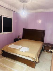 Un dormitorio con una cama grande con paredes moradas. en Appartement refait a neuf, en Bel Aroussi