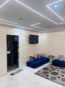 sala de estar con 2 sofás azules y TV de pantalla plana en Appartement refait a neuf, en Bel Aroussi