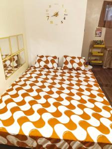 una camera da letto con un piumone arancione e bianco di Ciel's Haven Free Breakfast a Binangonan