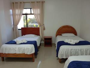 a bedroom with two beds and a window at Hostal Insular in Puerto Villamil