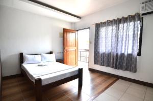 a bedroom with a bed and a window and a door at Highway to H Inn in Panglao Island