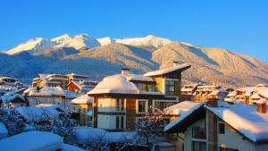 Un pueblo cubierto de nieve con montañas al fondo en Family Hotel Santo Bansko, en Bansko