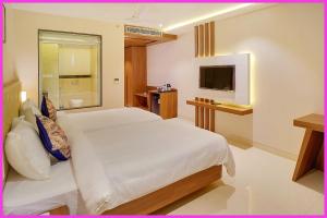 Un dormitorio con una cama blanca y un televisor. en New Marine Road BeachFront The Royal Bay Suite - Lift-Parking - Restaurant - Fully Air Conditioning Deluxe Rooms - A Best Luxuary Hotel, en Puri