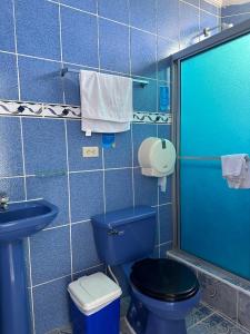 a blue tiled bathroom with a toilet and a sink at Hostal Insular in Puerto Villamil