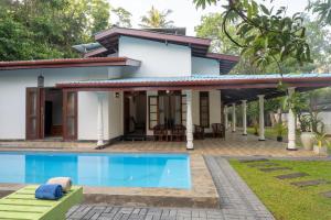 a house with a swimming pool in front of it at Sunset Reef Villa in Ratgama Hegoda