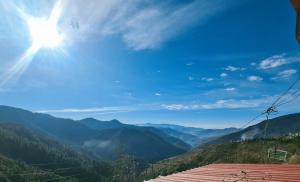 a view of a mountain valley with the sun in the sky at Narkanda Heights Rooms in Nārkanda +18 photos