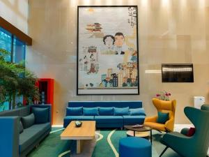 a lobby with blue couches and a painting on the wall at Magnotel Hotel Guangyuan Nanhe Bus Station Beijing Road in Guangyuan