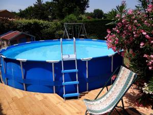a blue swimming pool with a ladder and a chair at Duplex En Provence in Vedène