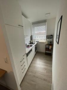 een kleine keuken met witte kasten en een spoelbak bij Gustavs Rooftop in Oldenburg