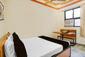 a bedroom with a bed and a desk and a window at Hotel O Gymkhana Dombivli Mumbai in Dombivli
