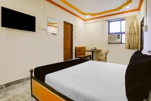 a bedroom with a bed and a table and a window at Hotel O Gymkhana Dombivli Mumbai in Dombivli +21 photos
