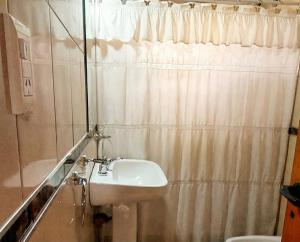 un bagno con lavandino e tenda da doccia di Brisas Serranas Departamentos a Villa Carlos Paz