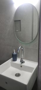 een wastafel in de badkamer met een ronde spiegel erboven bij The Nook in Pondicherry +22 foto's