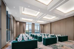 una sala de conferencias con mesas verdes y sillas blancas en Wyndham Garden Shanghai Songjiang, en Shanghái