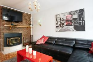 - un salon avec un canapé en cuir noir et une cheminée dans l'établissement Big Cozy House, à Montréal