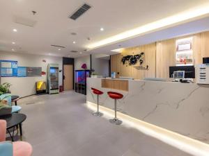 GreenTree Inn Express Lanzhou West Passenger Station Lanzhou Center في لانتشو: مطعم مع بار مع المقاعد الحمراء