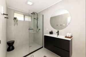 a bathroom with a shower and a sink and a mirror at 2-Bedroom Charm near Mater Hospital Pimlico Townsville in Aitkenvale