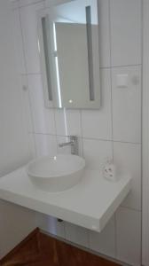Baño blanco con lavabo y espejo en Ferienhaus Benetik am Sonneggersee, en Sittersdorf