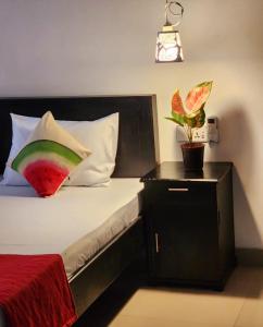 Un dormitorio con una cama con una almohada de sandía y una planta. en Tiny Villa Homestay - Only For Foreign Bookings, en Kurunegala