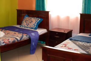 Habitación pequeña con 2 camas y mesita de noche en Calmchaos Jinja, en Jinja