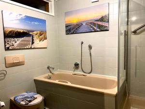 Un baño con bañera y ducha con dos cuadros en la pared. en Fewo Tilda im Haus Moselwelt, en Zell an der Mosel 26 fotos más