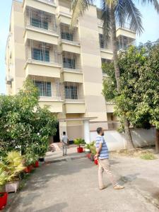 Un niño pequeño jugando béisbol frente a un edificio. en Unique Village, en Boāli
