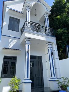 une maison blanche avec des colonnes bleues et un balcon dans l'établissement Habi Homestay Doc Let, 
