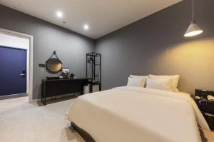 a bedroom with a large white bed and a black wall at 부띠끄 이틀호텔 in Cheongju