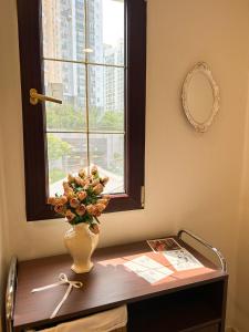 Un jarrón de flores sobre una mesa con una ventana. en 포켓서울 문래점, en Seúl