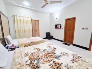 カラチにあるFamily Rose Guest House Millenniumのベッド2台と天井ファン付きの寝室 +27枚の写真