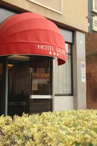 Una entrada de hotel con un toldo rojo sobre un arbusto. en Hotel Salieri, en Legnago