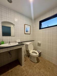een badkamer met toilet, wastafel en raam bij Florent House in Chiang Mai