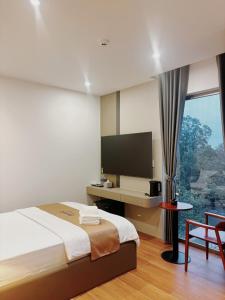 een slaapkamer met een bed en een bureau met een televisie bij Petit Hotel in Thu Dau Mot +45 foto's