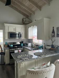 cocina con armarios blancos y encimera de granito en Haven of Rest Suite, en Nevis