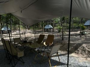 une table et des chaises sous un parasol blanc dans l'établissement Ko Kut Nature Camp, à Ko Kood