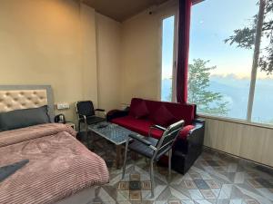 a bedroom with a bed and a couch and chairs at Hotel Sunrise Inn & Restaurant, Kanatal in Chamba