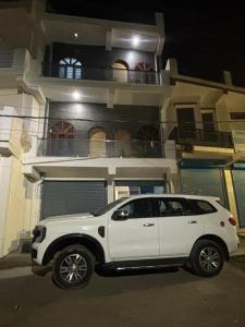a white suv parked in front of a house at shivoham Stays in Mājra