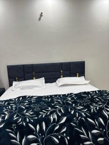 a bed with a black and white blanket and pillows at shivoham Stays in Mājra