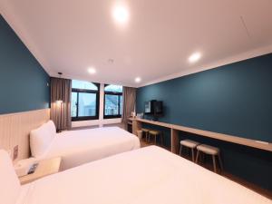 Una habitación de hotel con dos camas y una pared azul. en Yoshi Hotel - Tainan Station Branch, en Tainan 90 fotos más