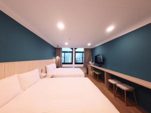 Una habitación de hotel con dos camas y una pared azul. en Yoshi Hotel - Tainan Station Branch, en Tainan