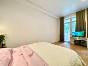 a white bedroom with a bed and a tv at Lux Garden Appartments in Kharkiv