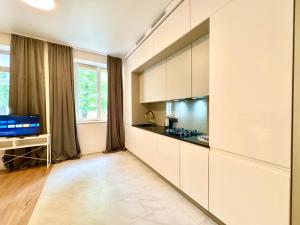 a kitchen with white cabinets and a television at Lux Garden Appartments in Kharkiv