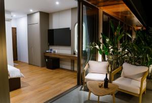 um quarto com uma televisão e duas cadeiras e uma mesa em Petit Hotel em Thu Dau Mot