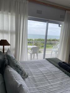 a bedroom with a bed and a view of the ocean at Jakaranda 22 apartment, Uvongo in Uvongo Beach