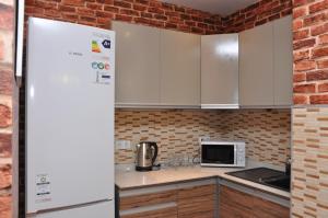 a kitchen with white cabinets and a brick wall at ART Hostel in Almaty